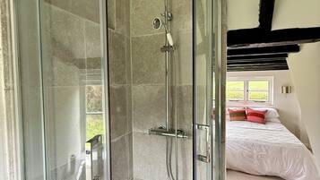 A glass-enclosed shower with a handheld showerhead and a handheld showerhead with a spray nozzle.