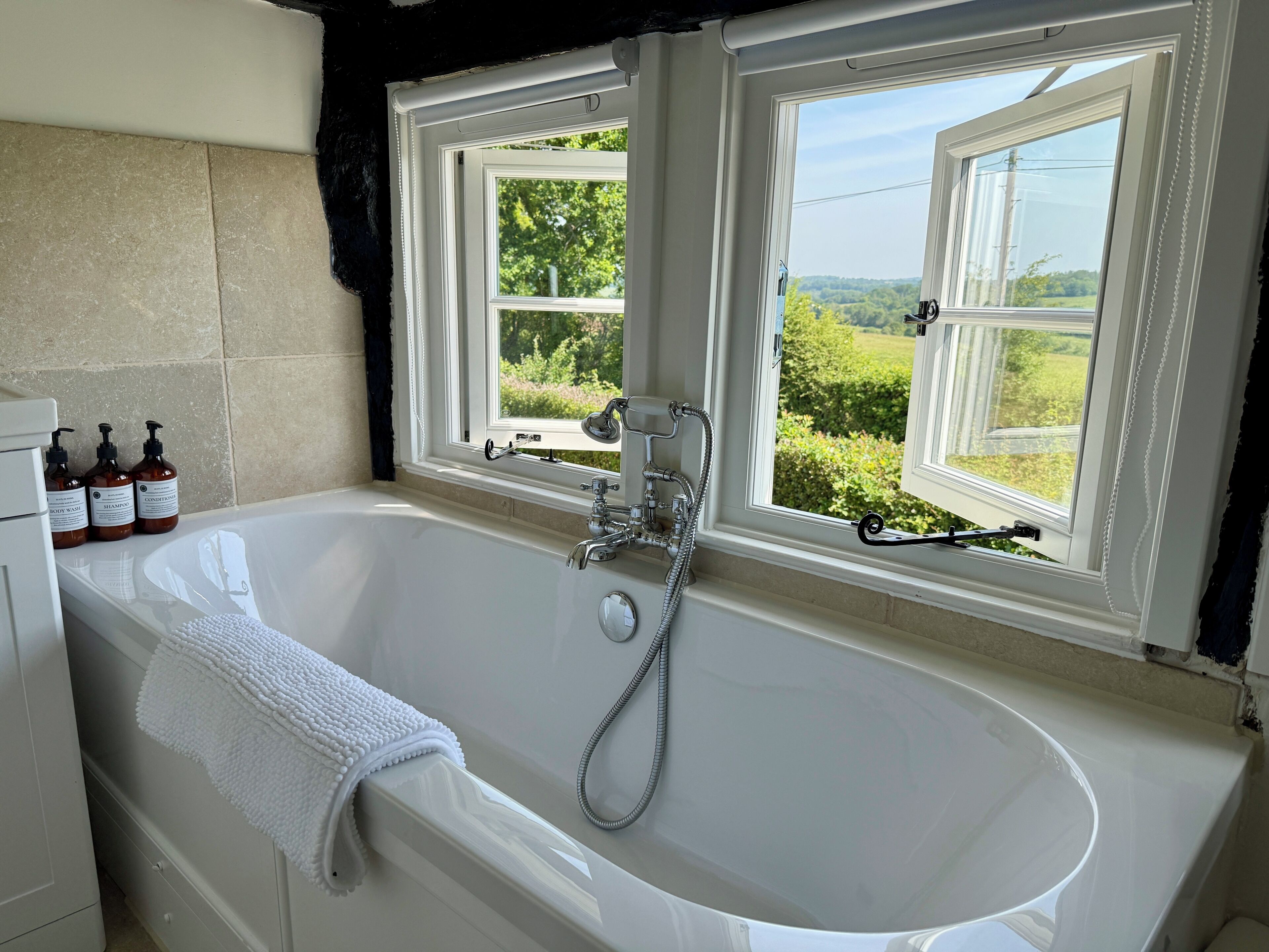 Une salle de bain avec une baignoire, deux fenêtres et des articles de toilette sur le comptoir.
