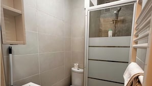 Un baño pequeño con inodoro, lavamanos y cabina de ducha.