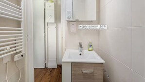 Uma casa de banho moderna com uma pia branca, um espelho e um porta-toalhas.