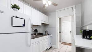 Una cocina con armarios blancos, un refrigerador, una estufa y un tostador.