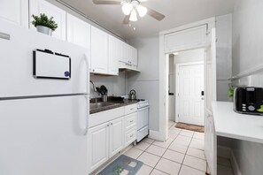 A kitchen with white cabinets, a refrigerator, a stove, and a toaster. - Downtown Apartment - Heart of SLC (Salt Lake City)