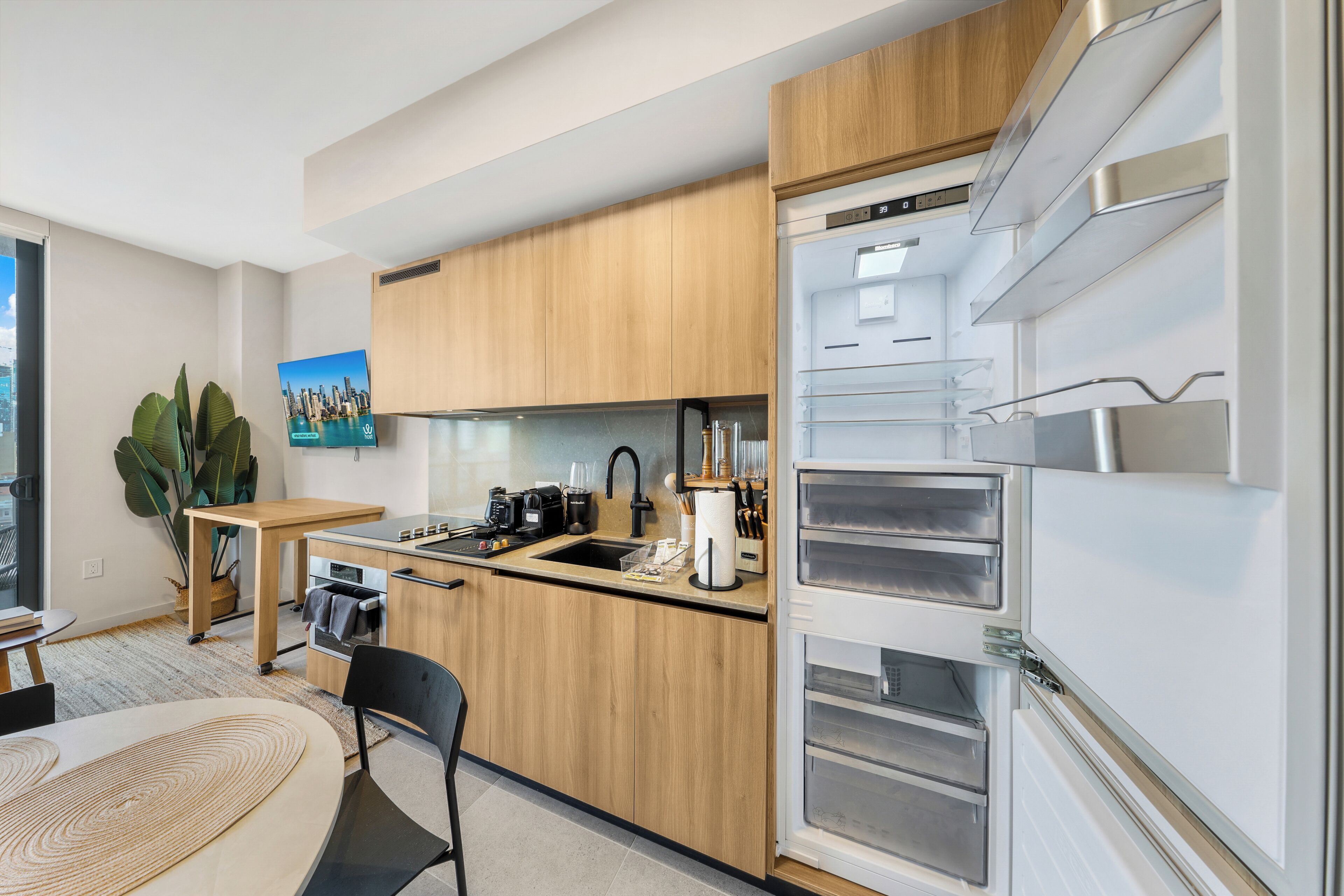 A modern kitchen with wooden cabinets, a built-in oven, a sink, and a refrigerator with multiple drawers.