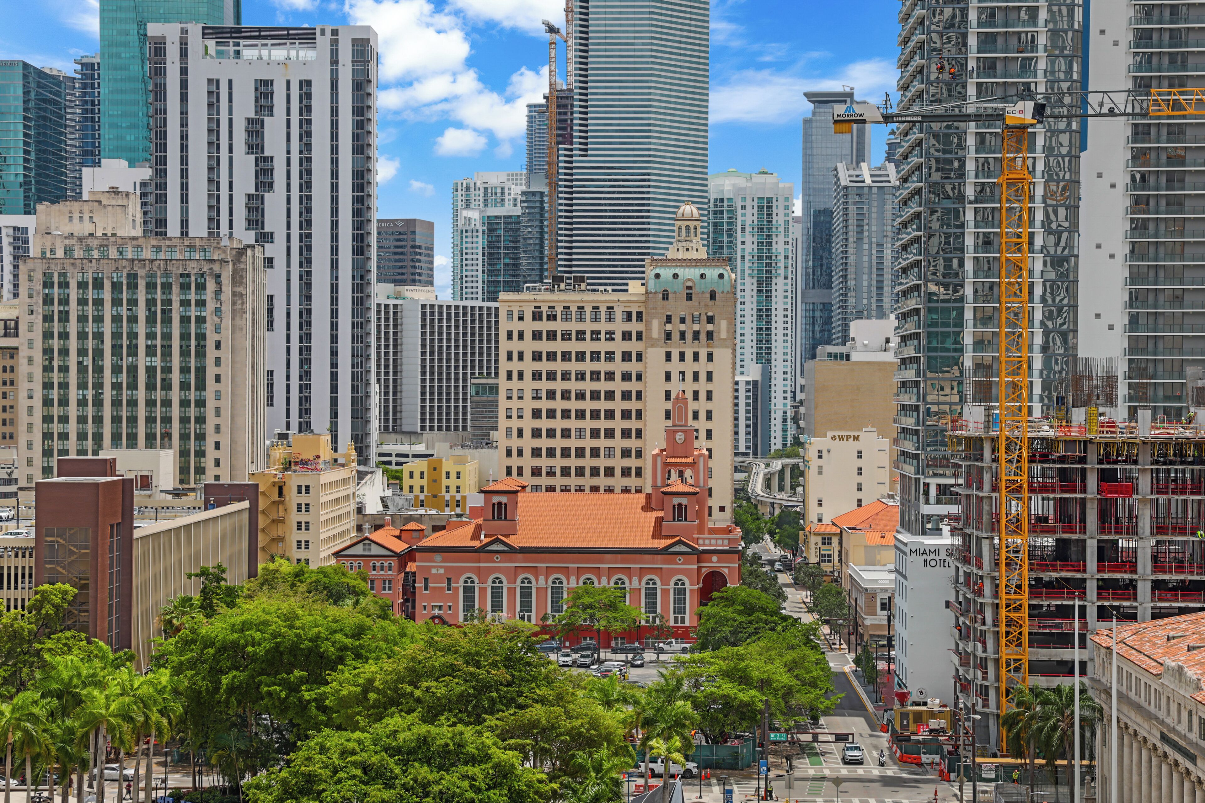 Un paisaje urbano con rascacielos, un edificio histórico de techo rojo y una grúa de construcción.