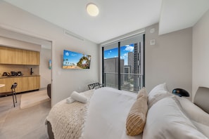Habitación de hotel moderna con cama, escritorio y ventana grande con vistas a la ciudad.
