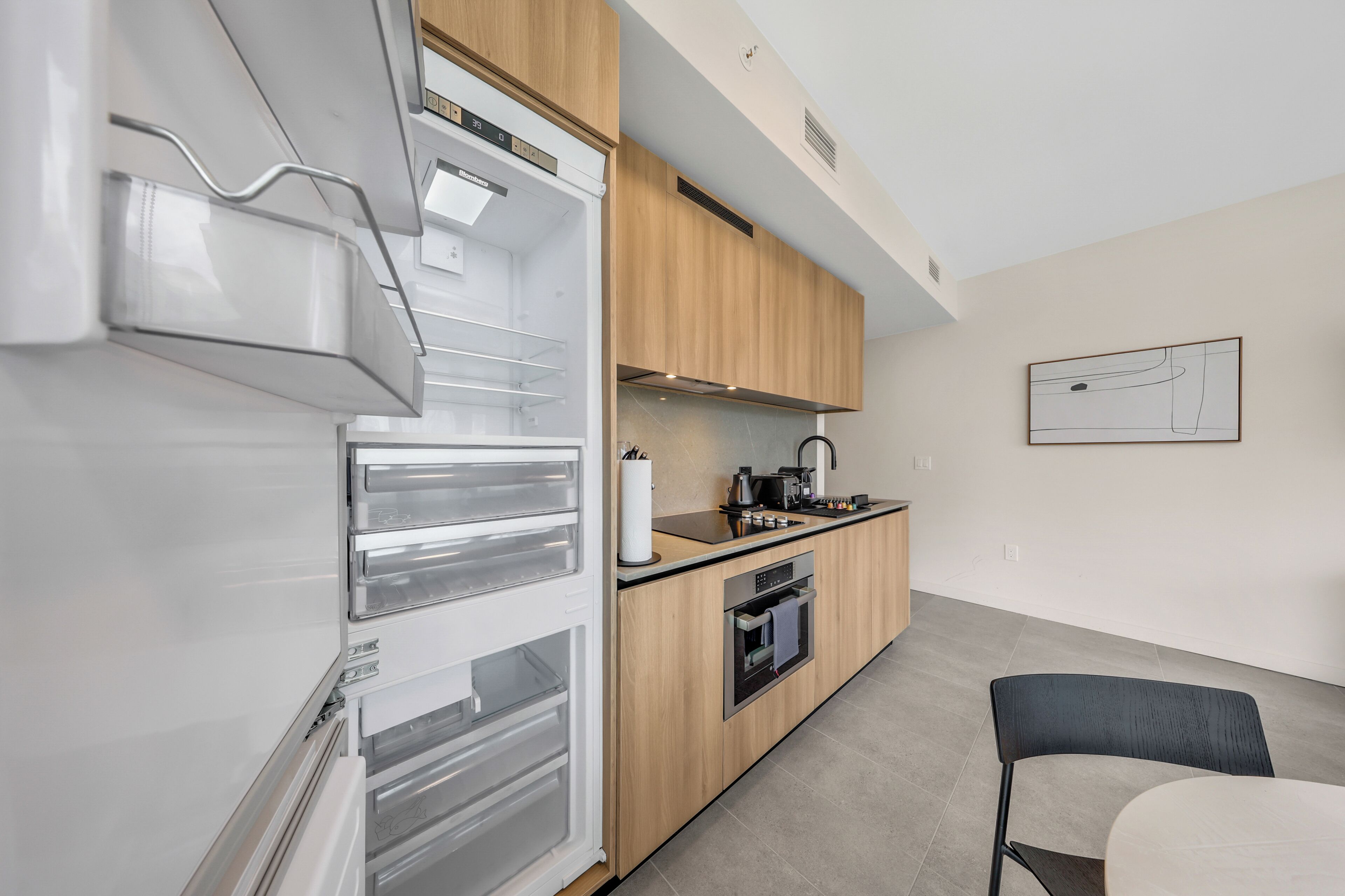 A modern kitchen with a built-in oven, a sink, and wooden cabinets.