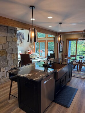 A modern kitchen with a large island, stone wall, and large windows. - Spacious 4-bedroom house with AC in peaceful Naples (Naples)
