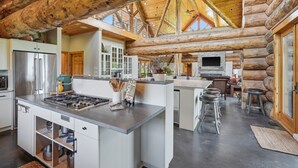 A spacious kitchen with a large island, stainless steel appliances, and a high ceiling with exposed wooden beams. - Luxury Lodge +Guest House + Sleeps 14  + World Cup (Greenwood)