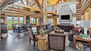 A spacious living area with a stone fireplace, leather sofas, and a dining area with wooden tables and chairs. - Luxury Lodge +Guest House + Sleeps 14  + World Cup (Greenwood)