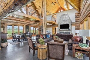 A spacious living area with a stone fireplace, leather sofas, and a dining area with wooden tables and chairs.