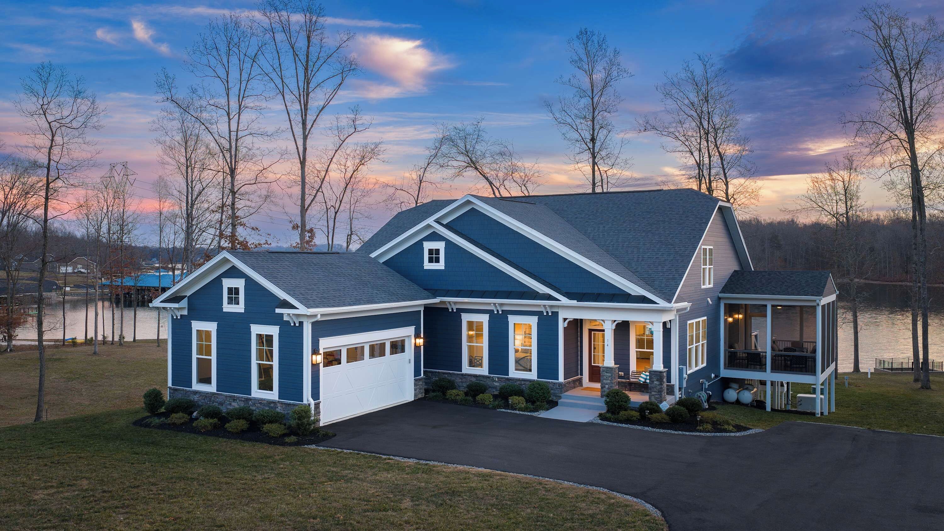 Exterior - The front of Fairview Lake Haven at dusk, garage, porch, and boathouse all lit against the darkening sky.