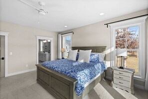 Primary Suite - The primary bedroom from the corner, showing the king bed, TV, ceiling fan, and ensuite doorway. - Fairview Lake Haven | New Waterfront Home | Private Side | 6BR/4BA | Boathouse & Dock (Mineral)