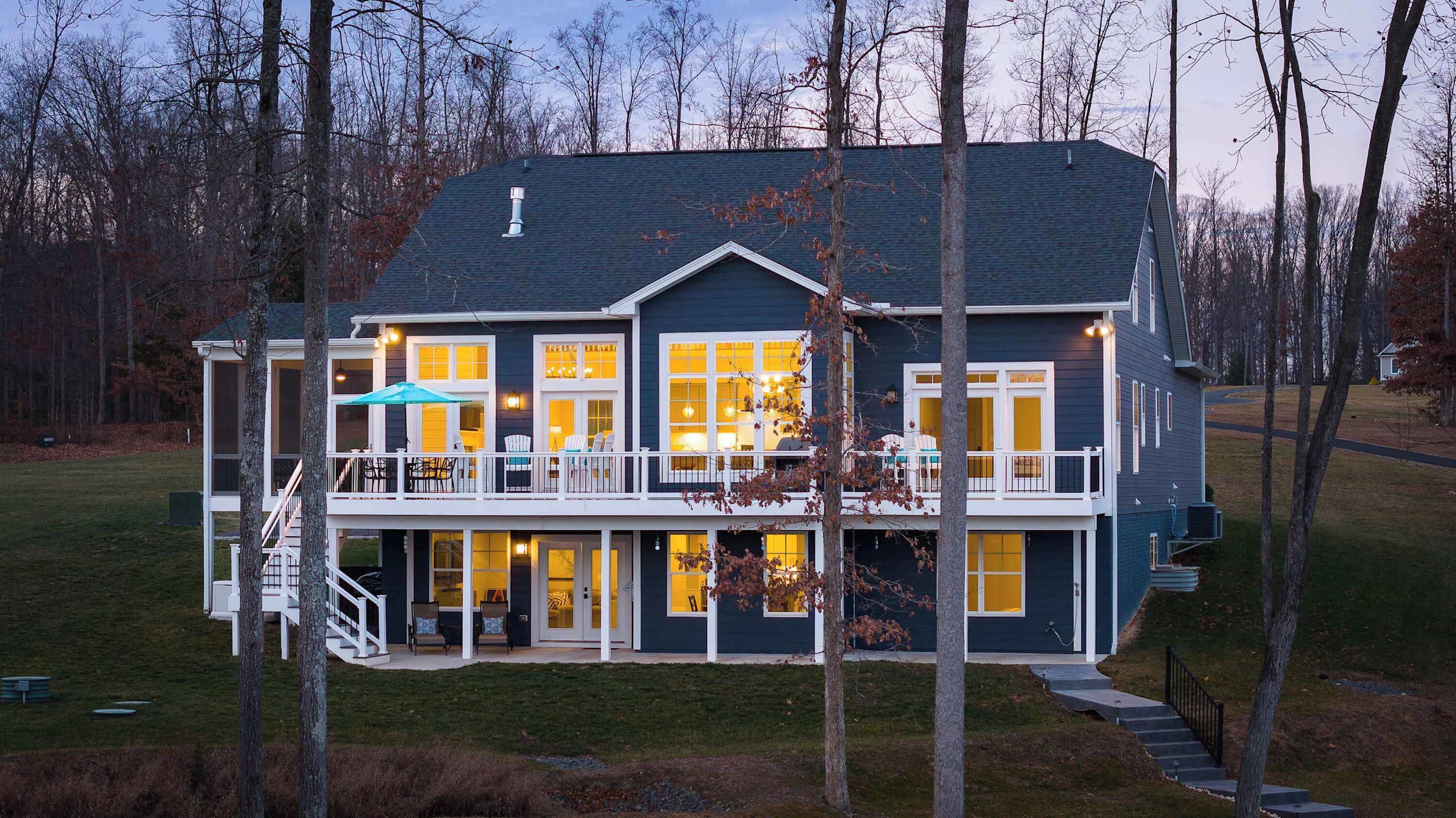 A two-story house with a balcony, large windows, and a covered patio area.