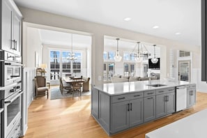 A modern kitchen with a large island, grey cabinetry, and pendant lighting. - Fairview Lake Haven | New Waterfront Home | Private Side | 6BR/4BA | Boathouse & Dock (Mineral)
