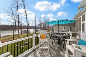Deck - Adirondack chairs and a dining table with teal umbrella face the lake and boathouse, a deck made for long afternoons. - Fairview Lake Haven | New Waterfront Home | Private Side | 6BR/4BA | Boathouse & Dock (Mineral)