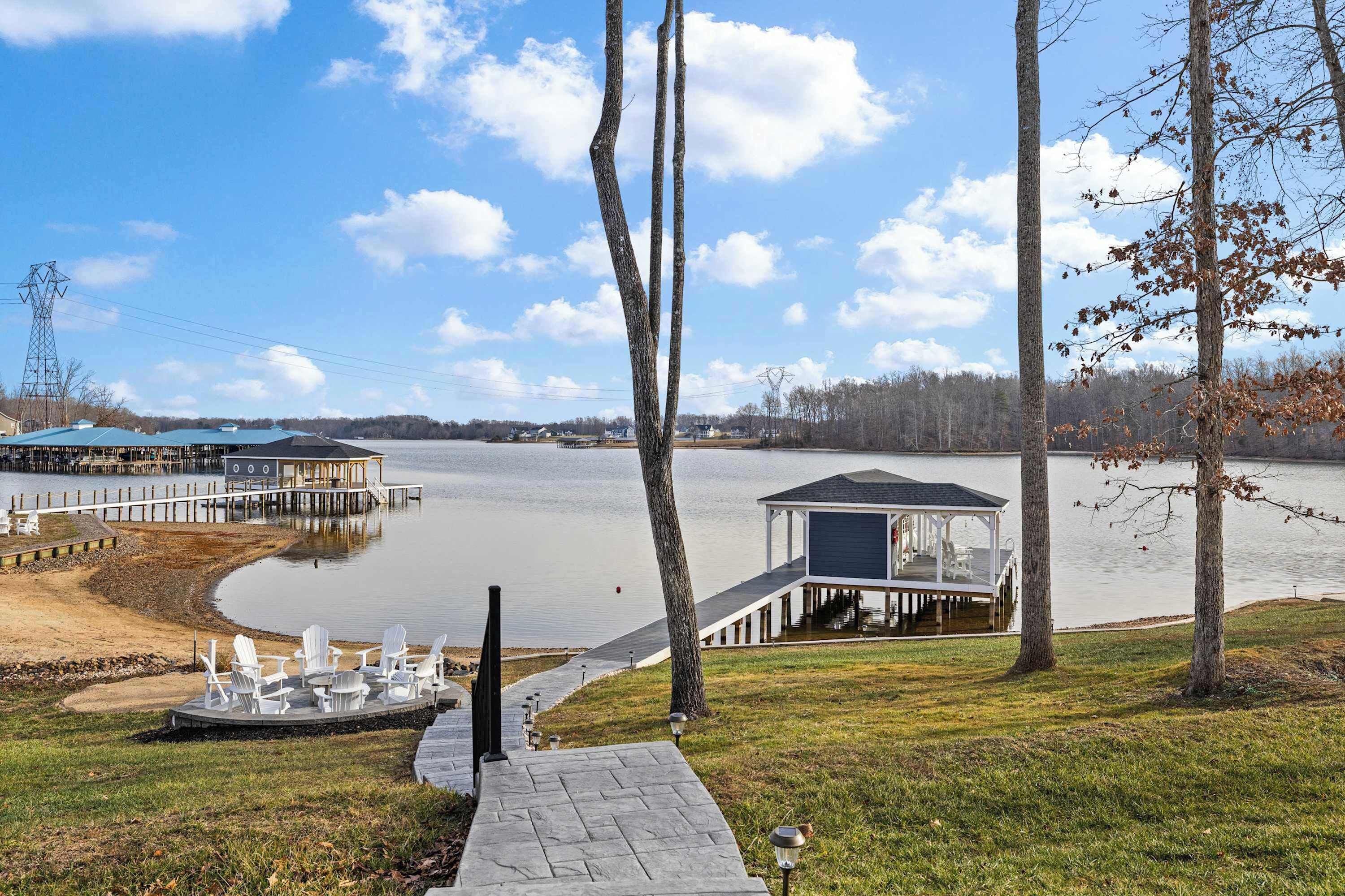 A lakeside property with a dock, a gazebo, and a pathway leading to outdoor seating.