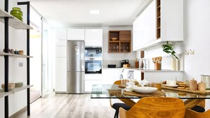 A modern kitchen with a glass dining table, wooden chairs, and a built-in oven. - Villa Tharros - Playa del Inglés (Playa del Ingles)