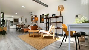 A spacious living area with a sofa, chairs, a dining table, and a kitchen in the background. - Villa Tharros - Playa del Inglés (Playa del Ingles)