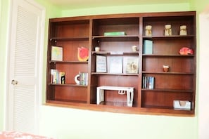 Ein Zimmer mit einer Holzregal, die mit Büchern, Dekoration und einem kleinen weißen Tisch bestückt ist.