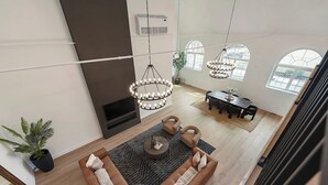 Een ruime woonkamer met een zithoek, een open haard, een eettafel en een kroonluchter.
