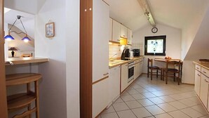 A kitchen with white cabinets, a wooden countertop, a dining table with chairs, and a clock on the wall. - Sonnenfleckerl Vacation Rental, 100 square meters (Drachselsried)