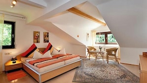 A bedroom with a sloped ceiling, a bed, a desk, and a chair. - Sonnenfleckerl Vacation Rental, 100 square meters (Drachselsried)