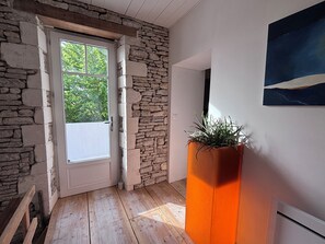 Ein Zimmer mit Steinwand, Holztür, Blumentopf und einem Gemälde an der Wand.