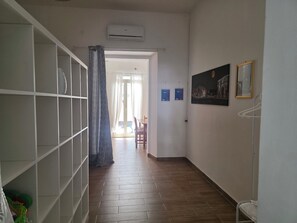 A hallway with a tiled floor, a white air conditioning unit, a patterned curtain, and a framed picture on the wall. - Maty's House 2 steps from the sea (40 mt) (Reggio Calabria)