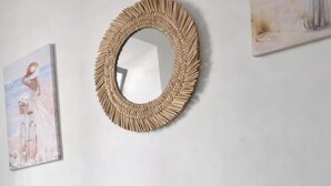 A room with a round mirror, a small white stool with a vase of pink flowers, and a blue bean bag chair. - Maty's House 2 steps from the sea (40 mt) (Reggio Calabria)