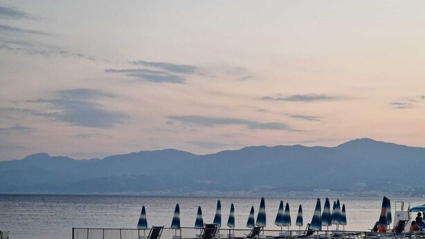 A beach with rows of beach chairs and umbrellas, a calm sea, and distant mountains. - Maty's House 2 steps from the sea (40 mt) (Reggio Calabria)