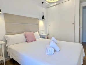 Ein Hotelzimmer mit einem großen Bett, einem Nachttisch, einer Lampe und einem Kleiderschrank.