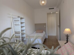 Une chambre à coucher comprenant un lit, une table de chevet avec une lampe, une armoire et une étagère murale.