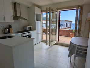 Eine moderne Küche mit Mikrowelle, Herd und Schränken, die zu einem Balkon mit Meerblick führt.