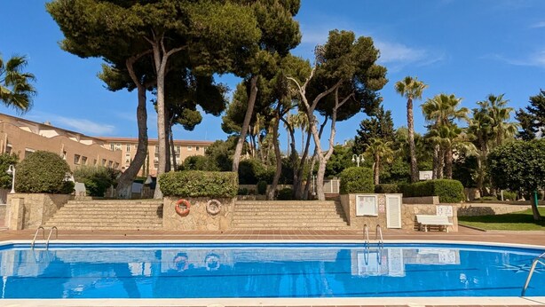 A swimming pool with steps leading up to it, surrounded by trees and a building in the background. - EVH114 Terraced House with Communal Areas (Altafulla)
