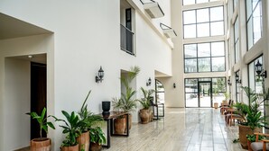 Eine großzügige Lobby mit großen Fenstern, Zimmerpflanzen und einer Sitzecke.
