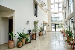 A spacious lobby with large windows, potted plants, and a seating area. - Moonlight Suite · Balcony · Tulum (Tulum)