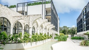 Ein modernes Gebäude mit Steinbögen, einem Wasserspiel und viel Grün.