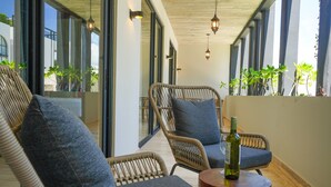 Ein moderner Lounge-Bereich mit Korbmöbeln, einem runden Holztisch und einer Weinflasche.