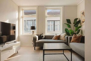A modern living room with a sofa, a coffee table, a TV, and large windows. - KS21 - 2BR Fairytale Bergen Hideaway (Bergen)