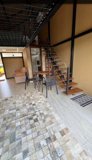 A modern interior with a staircase, a dining area, and a sofa. - Cabanas do Cerrado Cipó (Jaboticatubas)