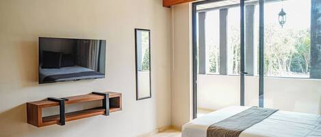 A bedroom with a bed, a TV mounted on the wall, a window, and a balcony.