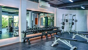 Une salle de sport équipée de bancs de musculation, d’haltères et d’appareils d’exercice.