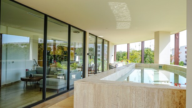 Un intérieur moderne avec un mur de verre, une piscine et un espace salon.