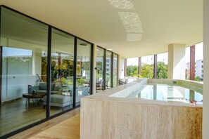 Un intérieur moderne avec un mur de verre, une piscine et un espace salon.