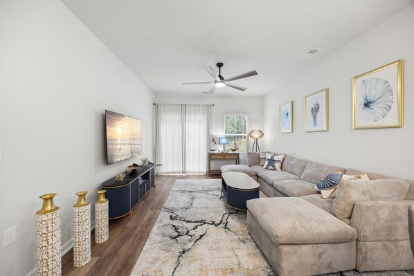 A living room with a sectional sofa, a coffee table, a TV, and decorative vases.