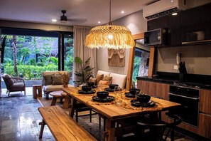 A modern kitchen with a dining area, large windows, and a view of greenery. - SwimUp Retreat in Aldea Zama Pool at Your Door & Beach Club (Tulum)