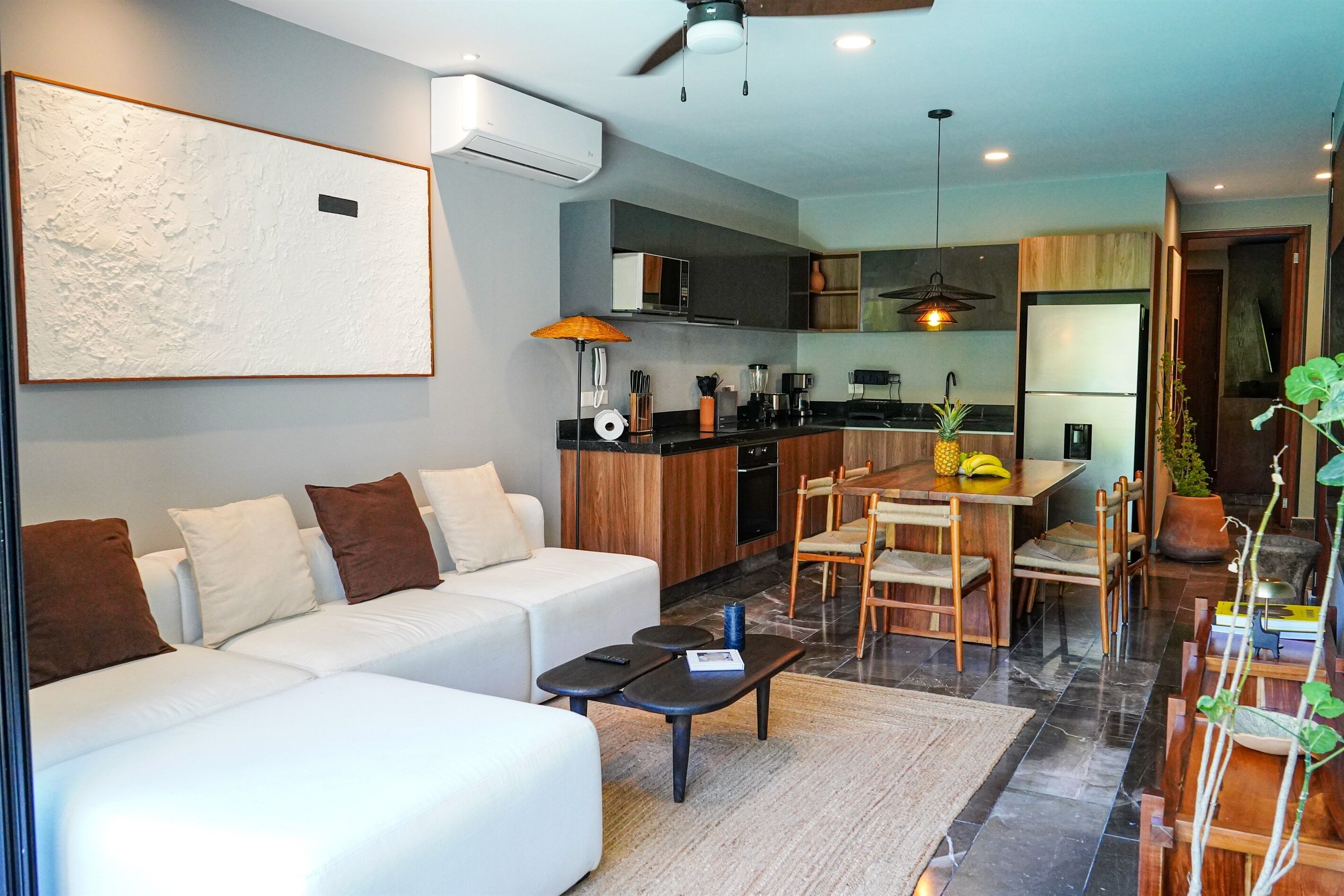 A modern living room with a sofa, coffee table, and dining area with chairs and a table.
