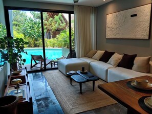 Ein modernes Wohnzimmer mit Sofa, Couchtisch und Blick auf einen Swimmingpool.