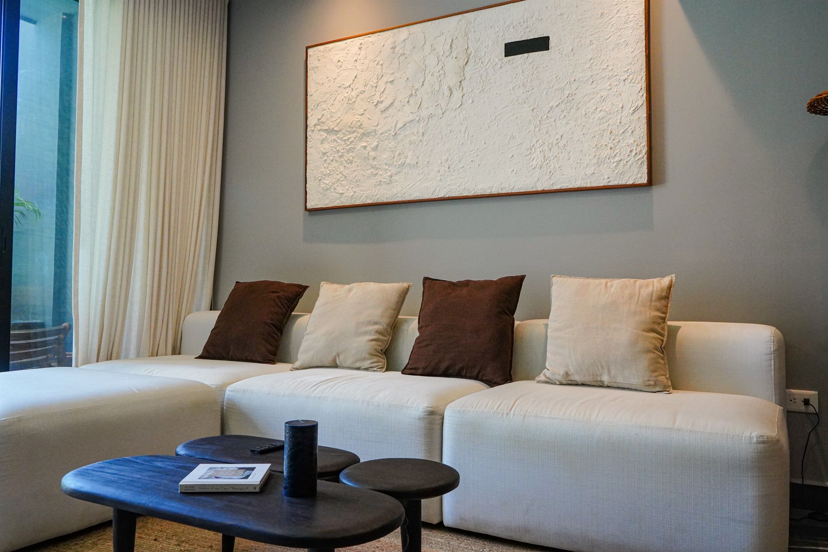 Una sala de estar moderna con un sofá modular, una mesa de centro y un cuadro abstracto grande en la pared.