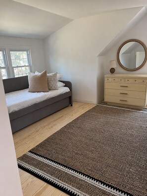 Un dormitorio con cama, cómoda, espejo y vistas al exterior.